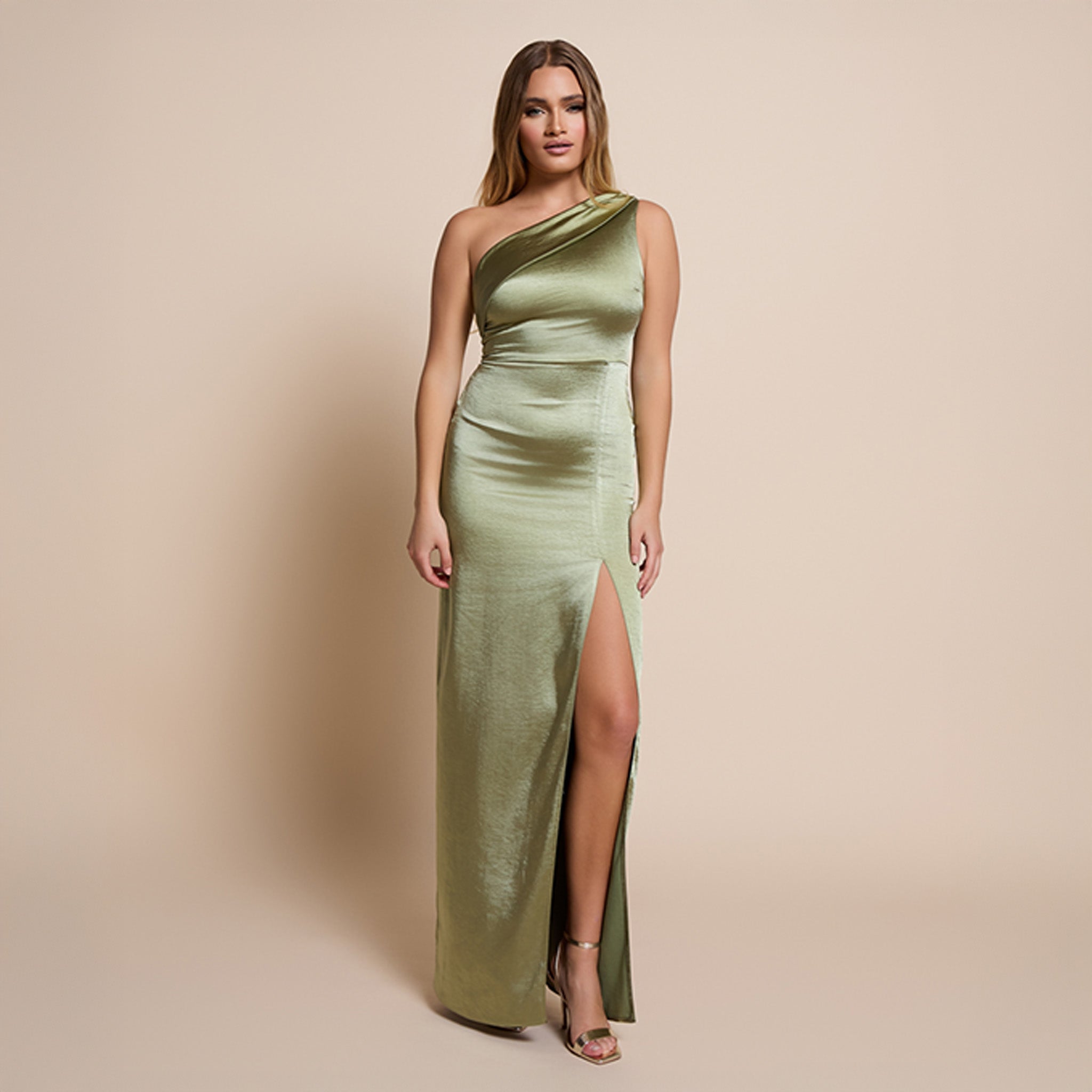Image of a model wearing the fliss maxi dress in olive satin on a beige background