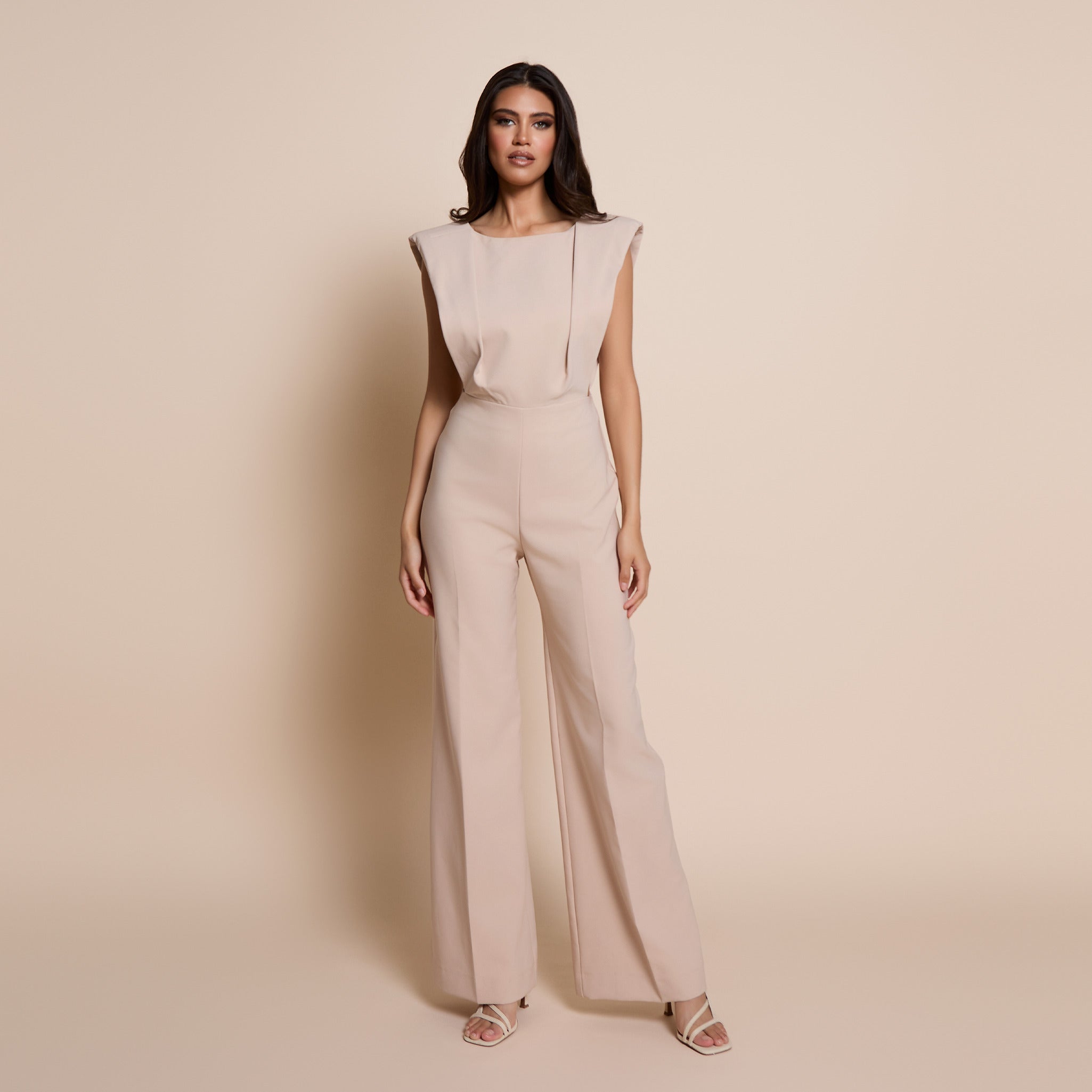 Image of a model wearing the vspr bronte open back wide leg jumpsuit in stone on a beige background