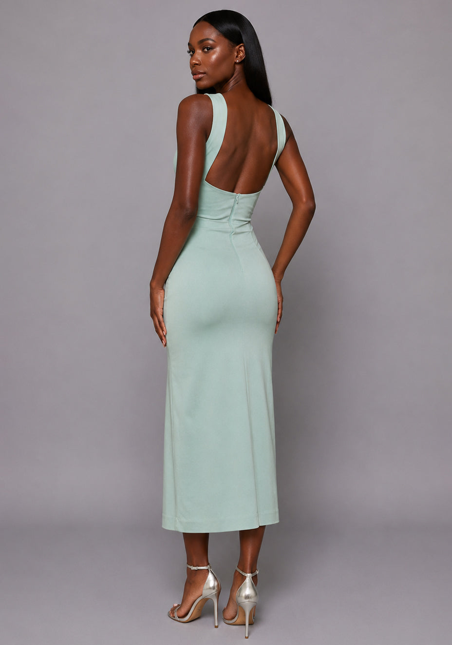 Side back image of a model wearing the VSPR Aida Cross Neck Open Back Sage Midaxi Dress, featuring the flattering open back design and sculpted fit in soft sage fabric against a grey studio backdrop.