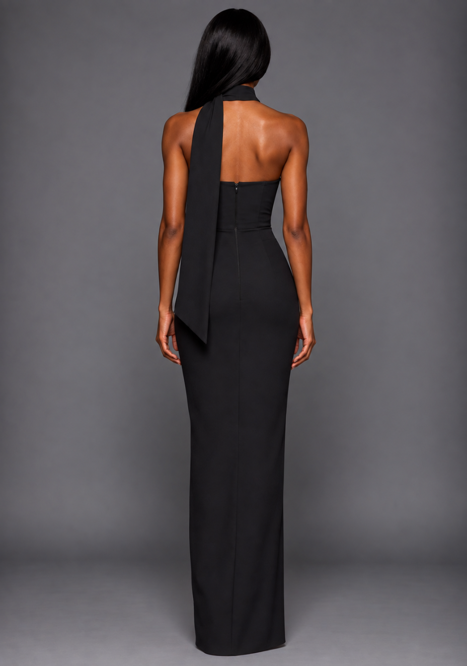 Back image of a model wearing the VSPR Cordula Scarf Detail One Shoulder Black Maxi Dress, showcasing its sleek slim-fit maxi silhouette and elegant black finish against a grey studio backdrop.