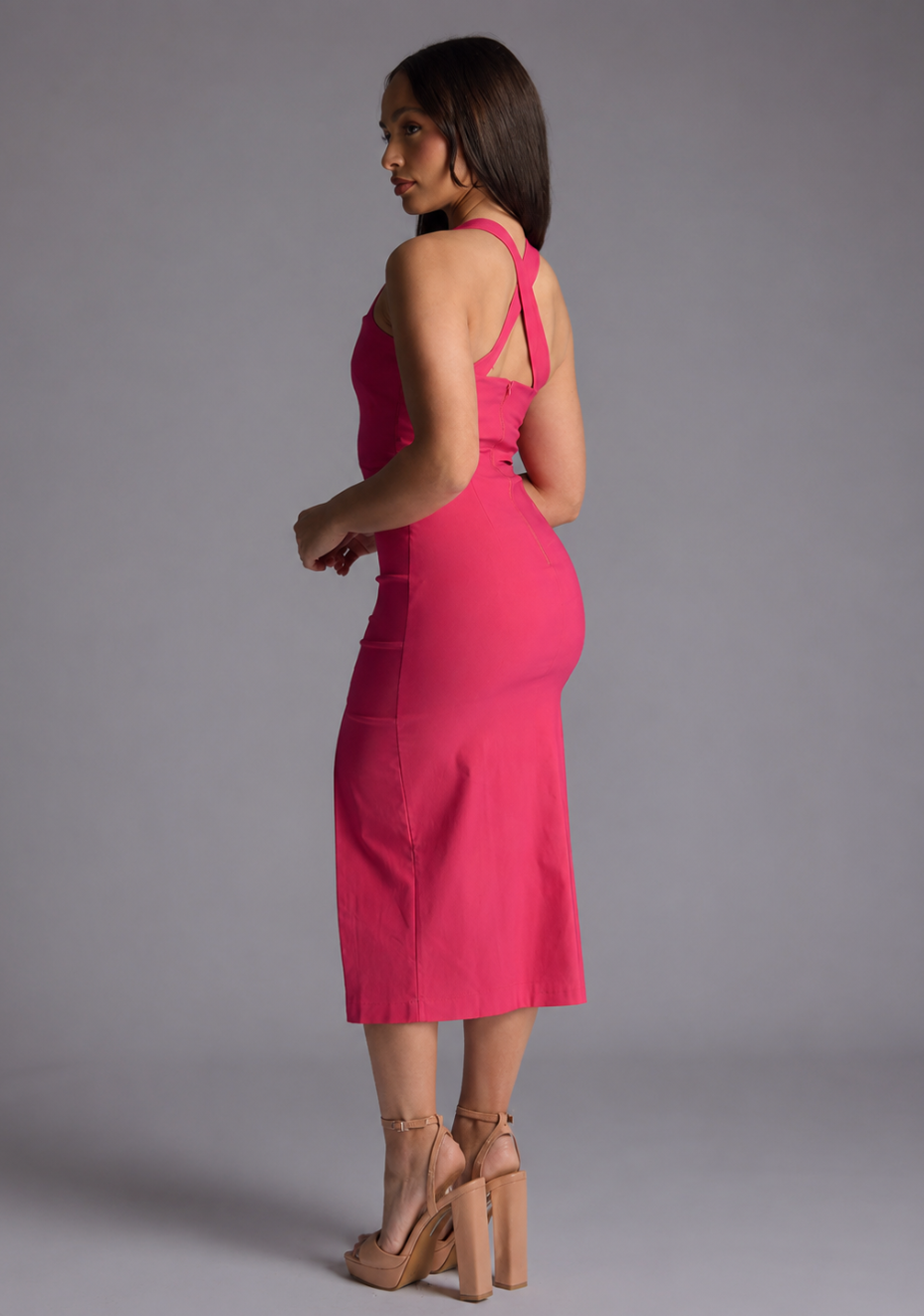 Woman wearing the Vesper Petite Poppy cerise sweetheart cross strap midaxi dress against a grey background, side back view
