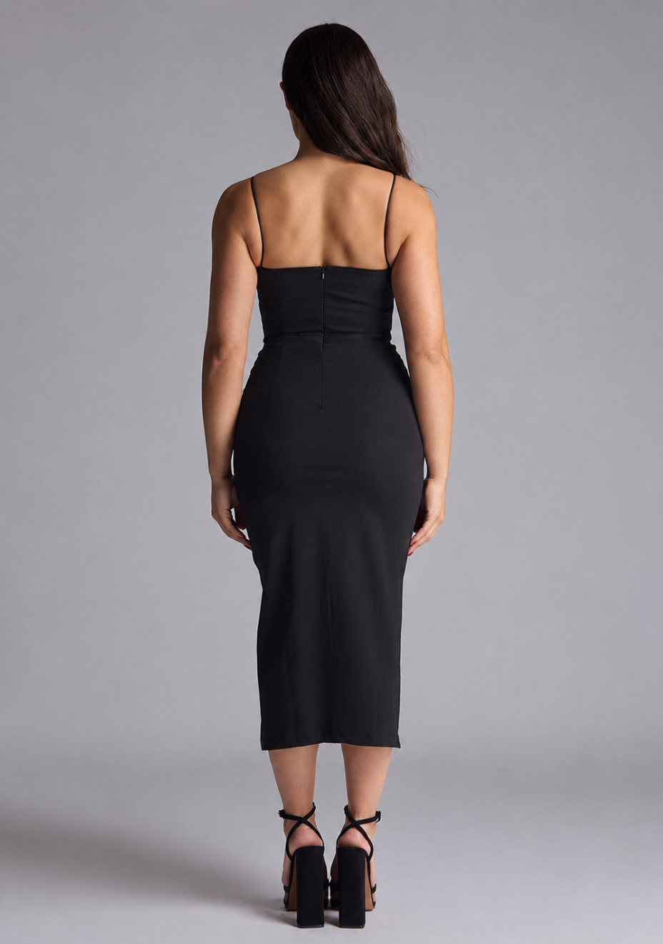 Woman wearing the Vesper Petite Tate black cami strap midaxi dress against a grey background, back view