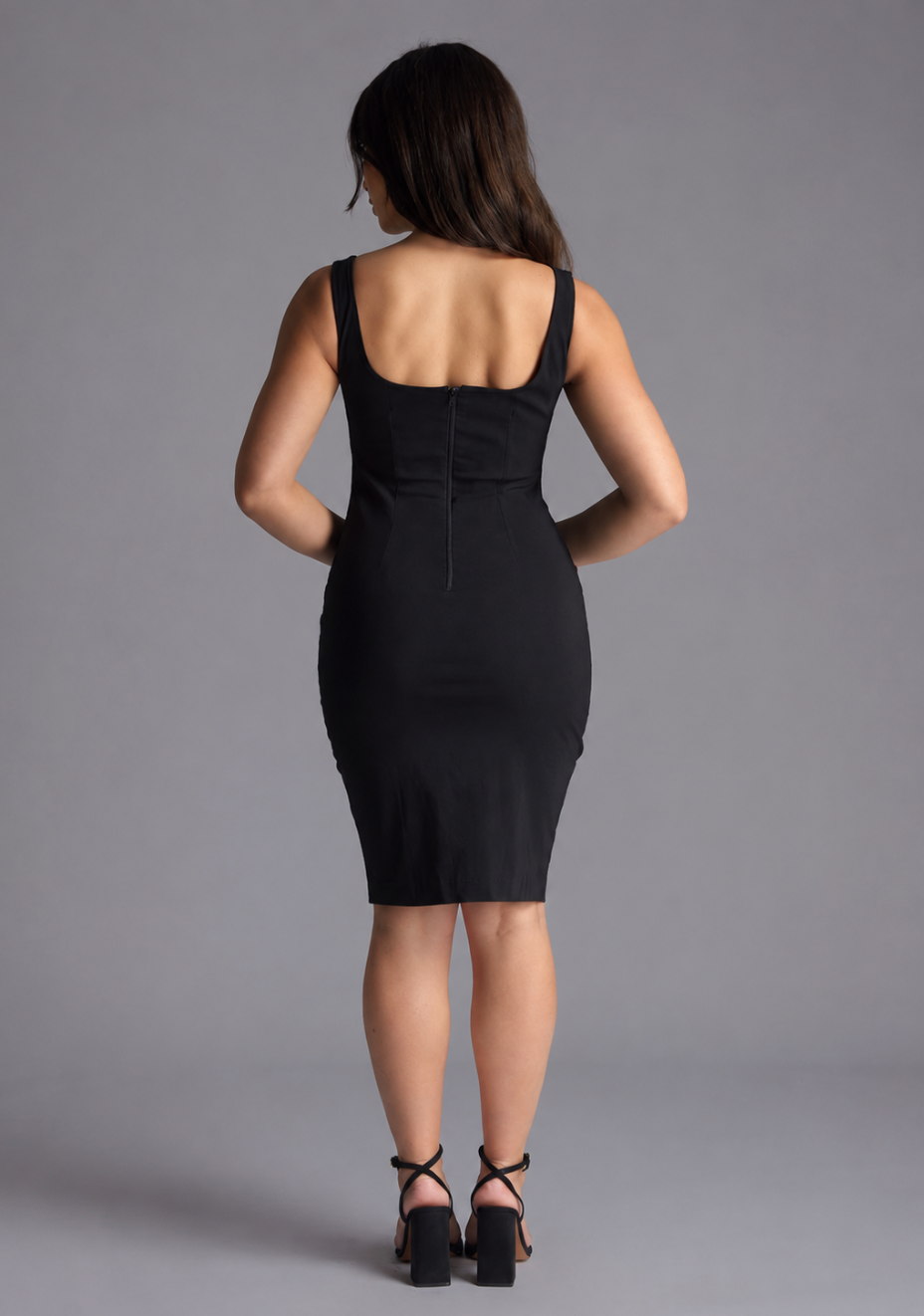 Woman wearing the Vesper Petite Zada black square neck midi dress against a grey background, back view