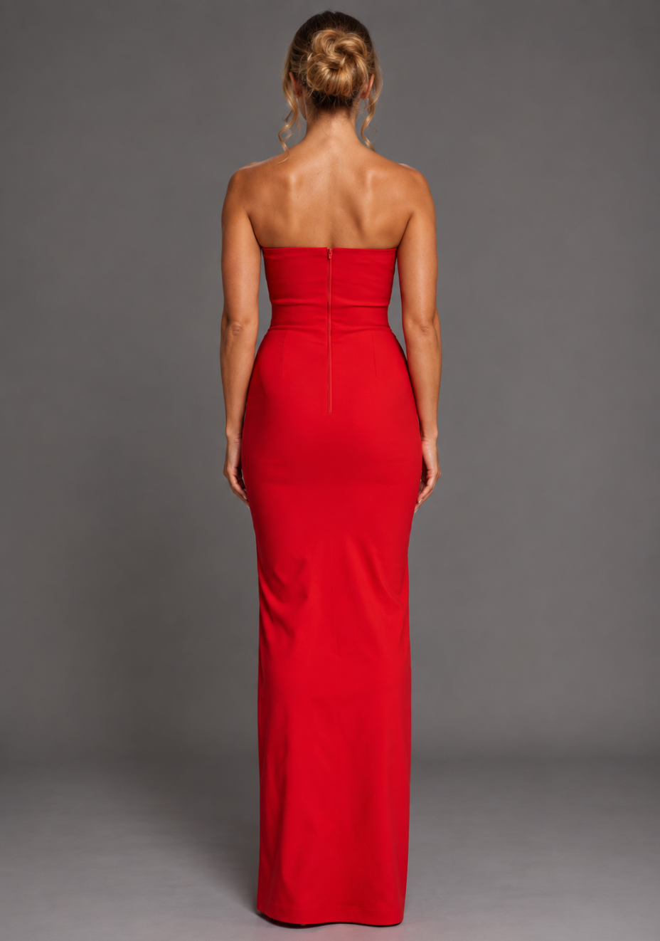 Back image of a model wearing the VSPR Thyme Strapless Red Maxi Dress in crimson red, showcasing its clean strapless design and sleek fitted maxi silhouette against a grey studio backdrop.