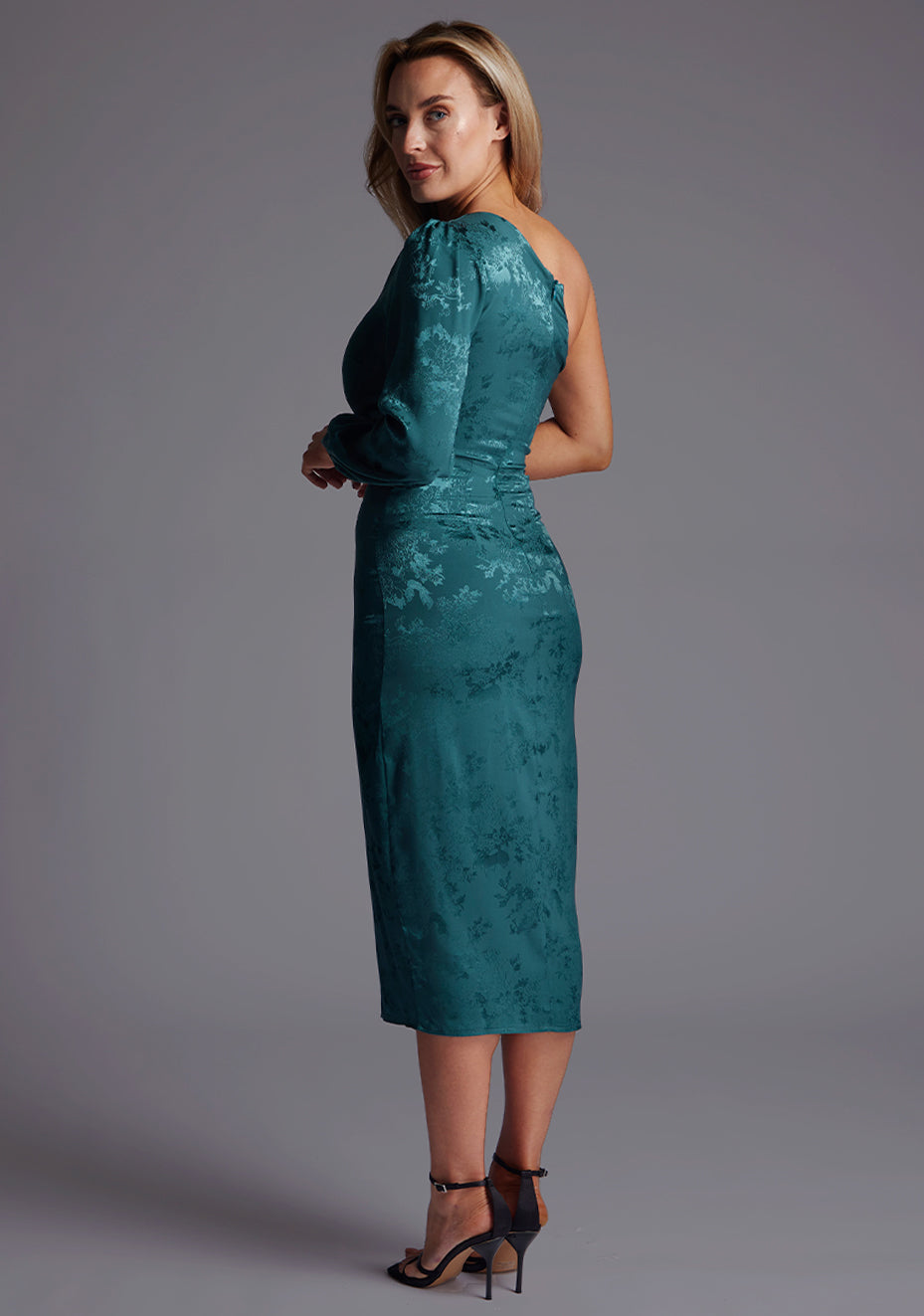 Side back image of a model wearing the Vesper Alice One Sleeve Midi Dress in Pine Green highlighting the clean lines and tailored midi silhouette.