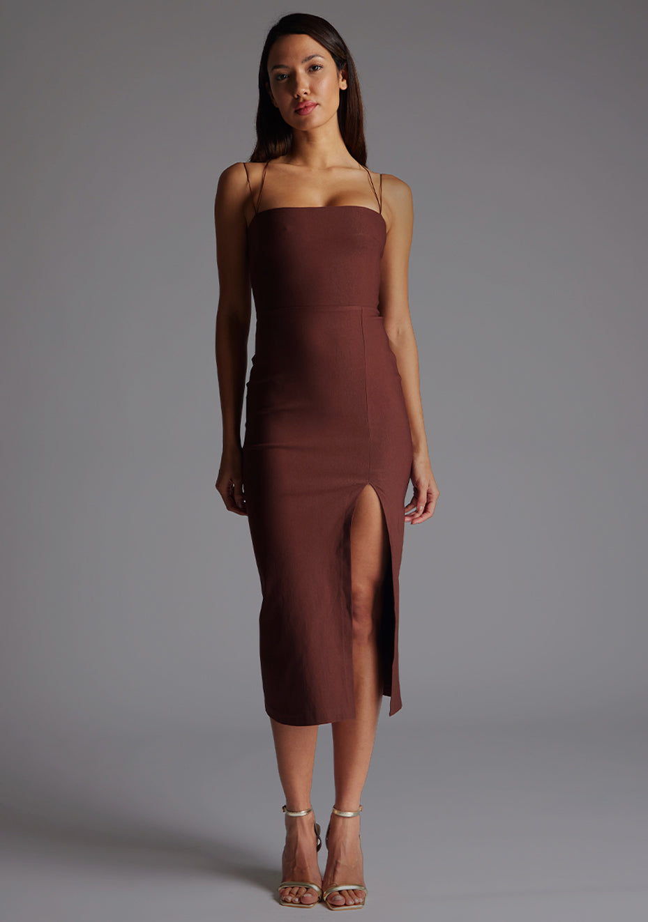 Front image of a model wearing the Vesper Alyssa Strappy Thigh Split Midaxi Dress in Chocolate, featuring a straight-across neckline, slim straps, and a softly contoured silhouette, styled against a neutral studio backdrop.