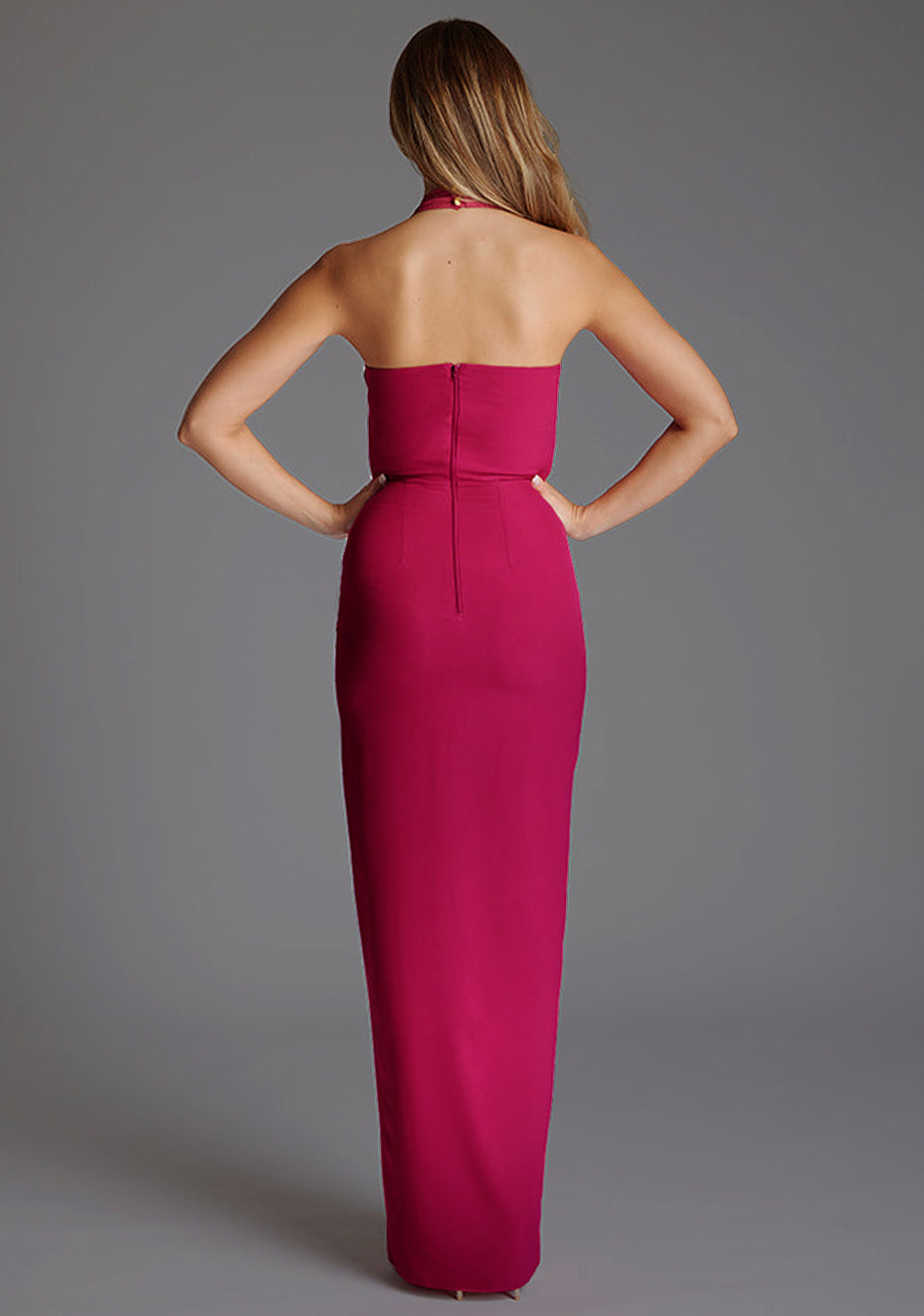 Back image of a model wearing the Vesper Amira Halter Neck Maxi Dress in Raspberry, showcasing the halter neckline fastening and clean, flowing maxi-length silhouette.