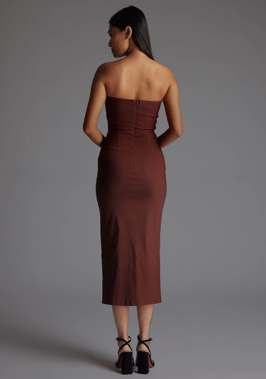Back image of a model in the Vesper Andorra Strapless Midaxi Dress in Chocolate, emphasizing the streamlined back profile, elegant fit, and timeless midaxi hemline.