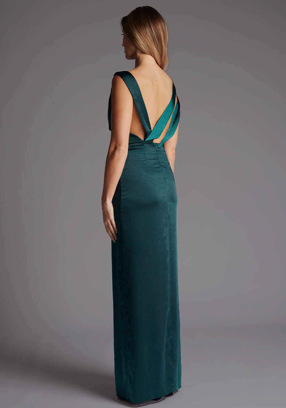 Side back view showing the deep V open back of the pine green satin maxi dress, with wide satin straps crossing at the lower back and a fitted straight skirt.