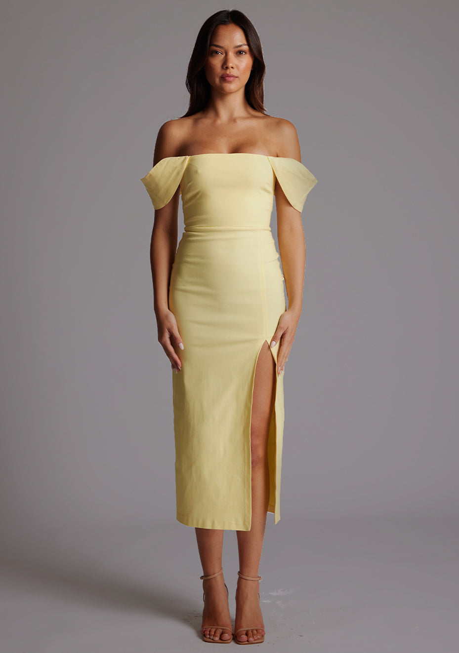 Front image of a model wearing a yellow Bardot midaxi dress with a stunning Bardot neckline, with armbands and a front skirt split. The design featured is the VSPR Astra Yellow Bardot Midaxi Dress.