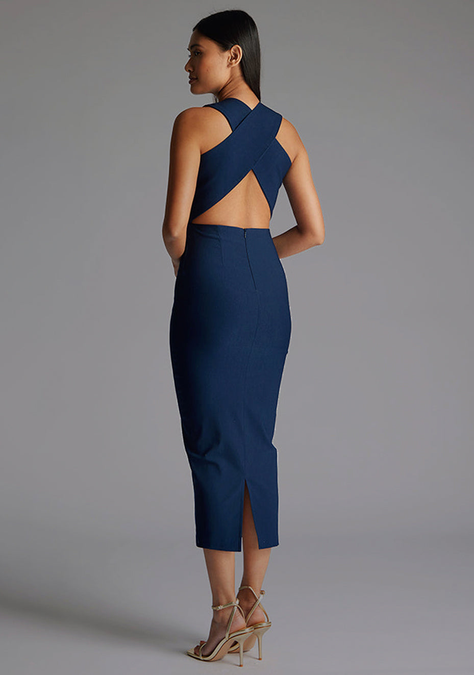 Side back image of a model wearing the Vesper Aubrey Plunge Midaxi Dress in Navy highlighting crisscross strap, refined bodycon cut and polished navy finish.