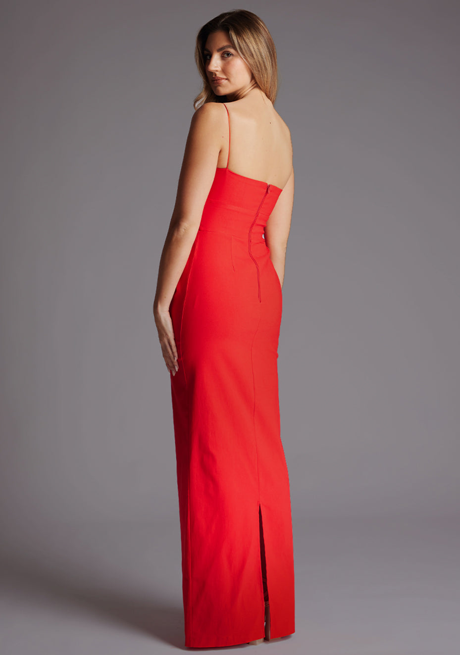 Back quarter image of a model wearing a red square neck maxi dress with a chic straight neckline, delicate thin straps and sleek slim fit. The design featured is the Vesper Bergen Maxi Dress
