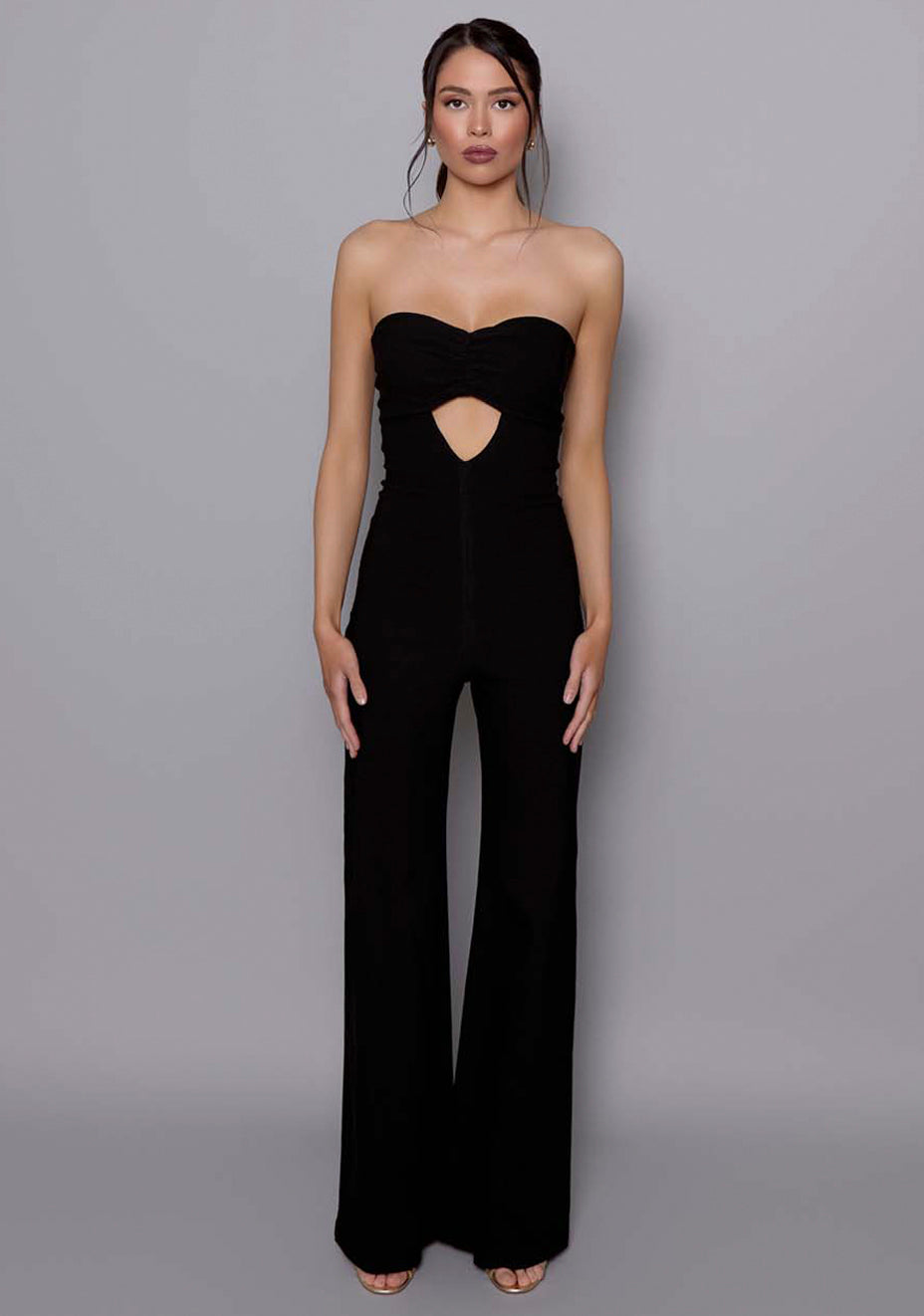 Model wearing the VSPR Betsy black wide-leg jumpsuit featuring a ruched bandeau neckline and front keyhole cut-out, styled against a neutral studio backdrop.