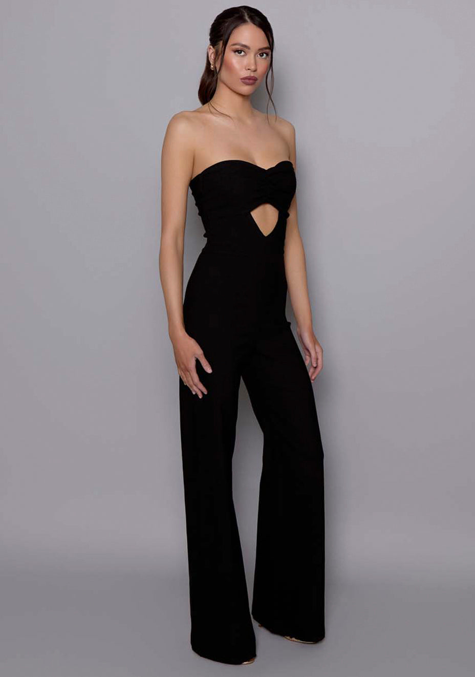 Side-front view of the VSPR Betsy black jumpsuit showcasing the structured bandeau top, flattering waistline, and flow of the wide-leg trousers.