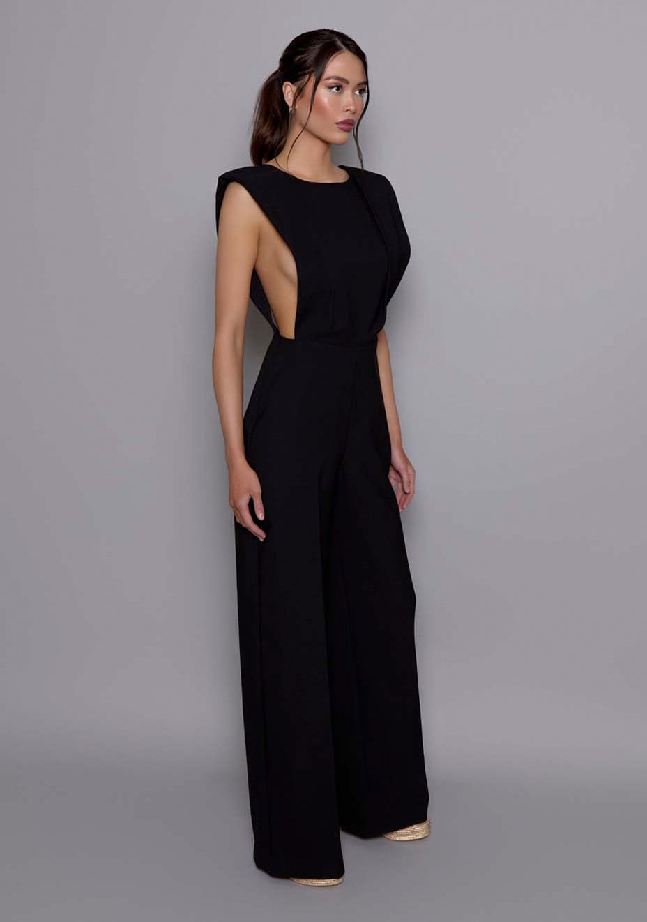 Side-front view of the VSPR Bronte Black Jmpsuit highlighting the confident shoulder structure, fluid wide-leg fit, and the clean architectural silhouette.