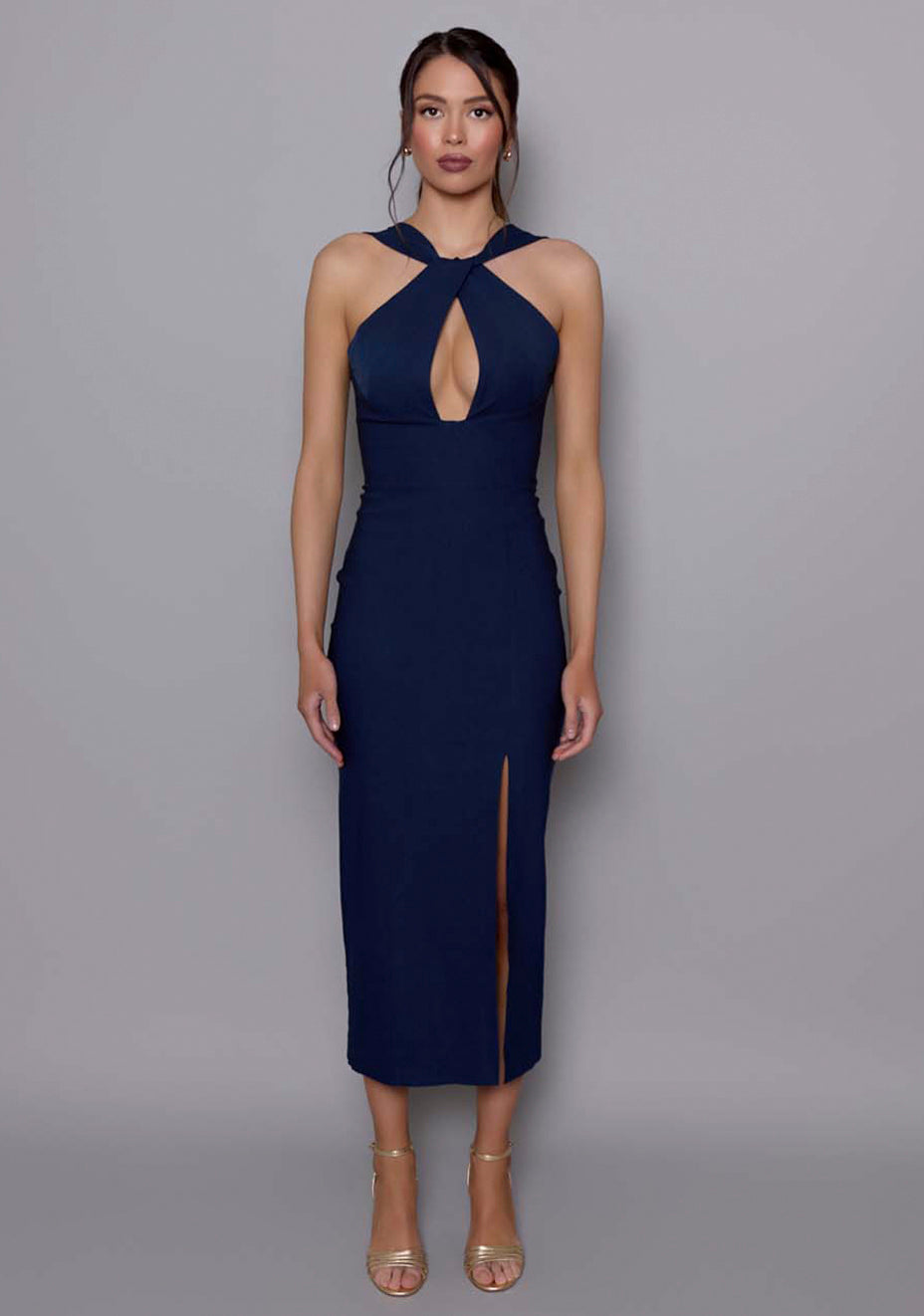 Model wearing the VSPR Carter navy midaxi dress featuring a halterneck twist neckline and plunging front cut-out, styled against a neutral studio backdrop.