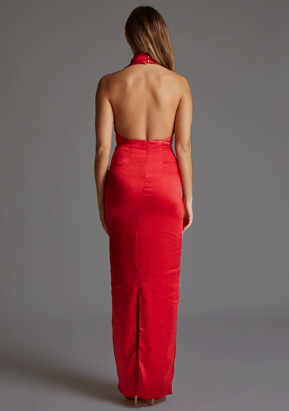 Back image of a model wearing the Vesper Colby Satin Maxi Dress in Red, featuring a striking open back, sleeveless cut, and elongated bodycon fit.