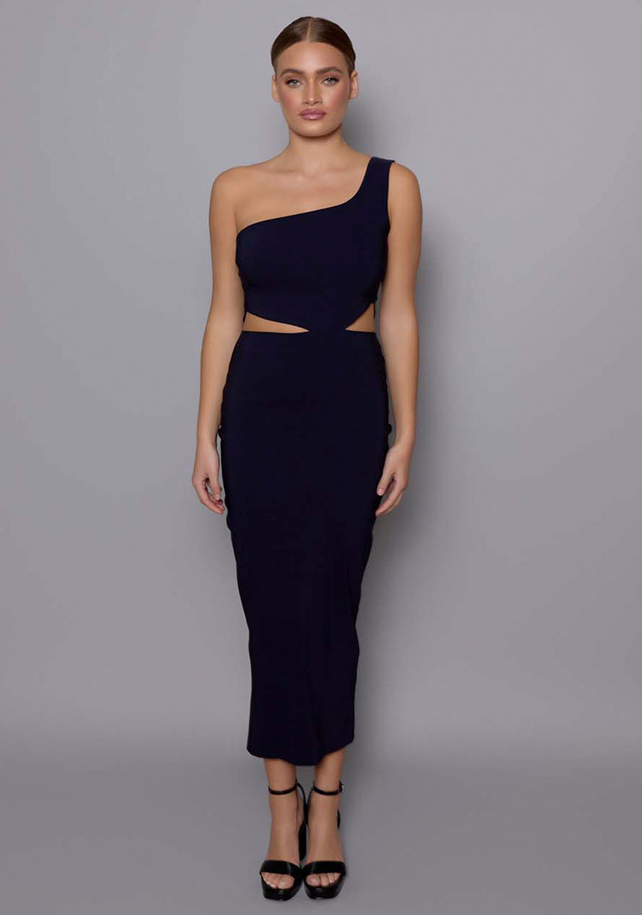 Model wearing the VSPR Eliza navy midaxi dress featuring an asymmetric one-shoulder neckline and sharp waist cut-outs, posed against a neutral studio background.