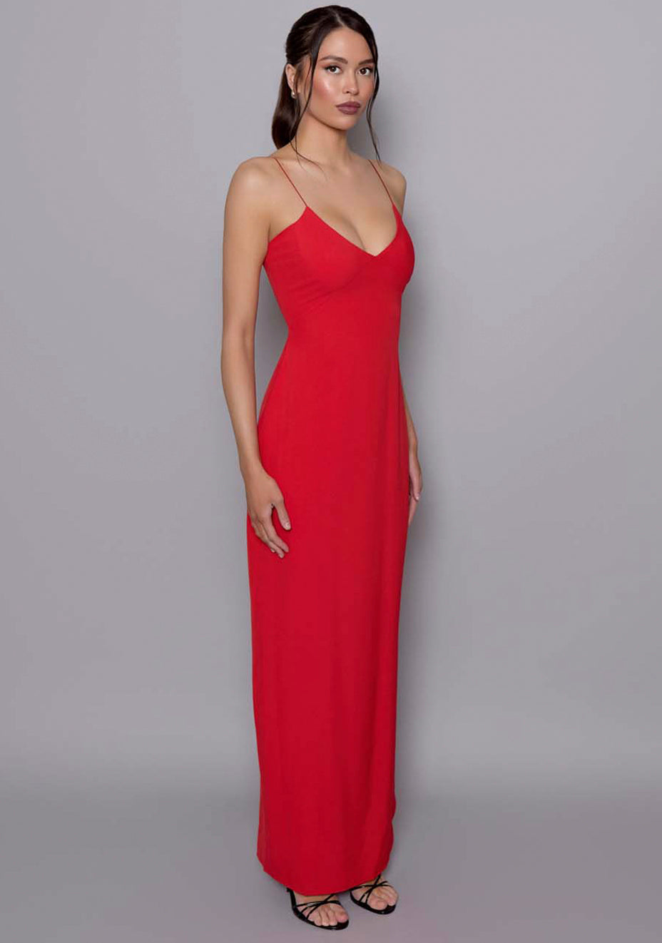 Side-front view of the VSPR Ellesse scarlet red maxi dress showing the figure-skimming fit, plunging neckline, and elegant strap placement for a refined, fluid look.