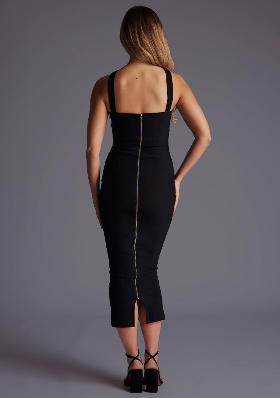 Back image of a blonde model wearing a Black Midaxi Dress with a criss-cross neckline, a tasteful keyhole detail, and a slim fit design. The design featured Vesper Hudson Cross Strap Boydcon Midaxi Dress in Black.