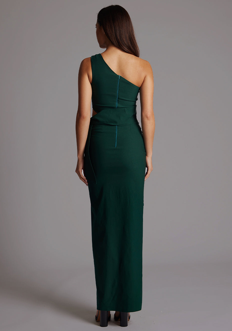 Back image of a model wearing the Vesper Lisbeth One Shoulder Maxi Dress in forest green, showcasing the sleek open shoulder line and flowing maxi silhouette.