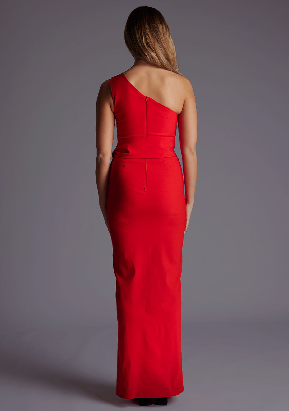 Back image of a model wearing the Vesper Lisbeth One Shoulder Maxi Dress in Red with a sleek, minimal back design and floor-length silhouette.