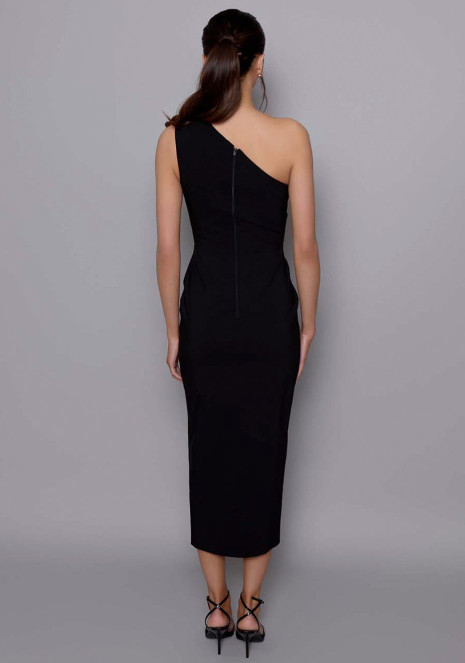 Back view of the VSPR Madison black dress with a sleek zip closure and smooth back panel, revealing the clean lines and fitted silhouette of the one-shoulder design.