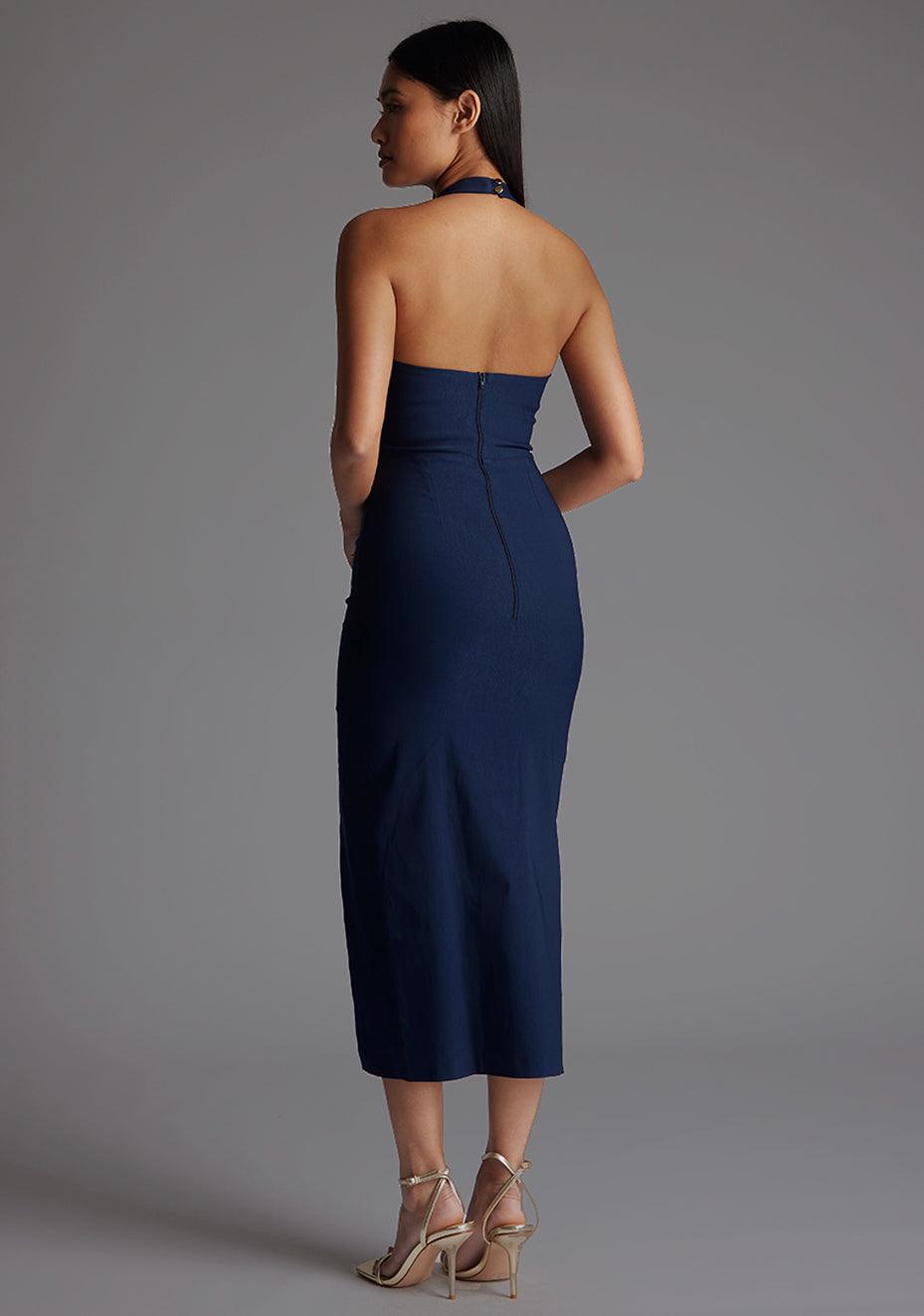 Side back image of a model wearing the Vesper Maria Halter Midaxi Dress in Navy, revealing the sleek back button fastening and tailored fit.