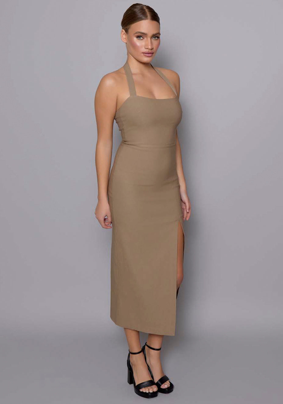 Side-front view of the VSPR Maria taupe midaxi dress, emphasizing the sculpted silhouette, halterneck structure, and sleek thigh split for a refined yet sensual look.
