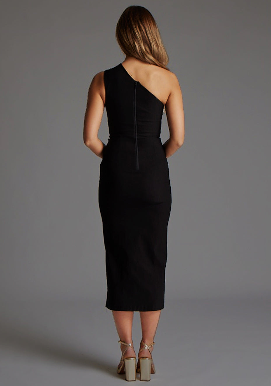 Back image of model wearing a Black Midaxi Dress with a asymmetric neckline, one-shoulder design features a tasteful cut out, while the front skirt split adds a chic. The design features Vesper Ollie One Shoulder Cut Out Midaxi Dress With Thigh Split in Black.