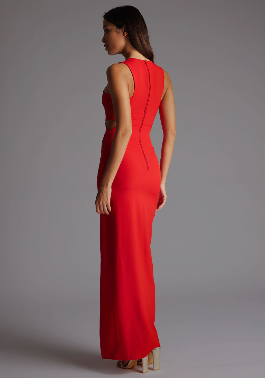 Side back image of a model wearing the Vesper Paige Cut Out Maxi Dress in Red, revealing the open waist detail and smooth back fit.