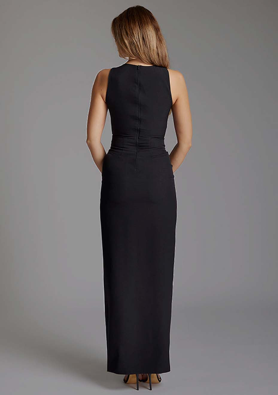 Back image of a model wearing the Vesper Polly Asymmetrical Maxi Dress in Black featuring a clean centre-back zip and flowing maxi silhouette.