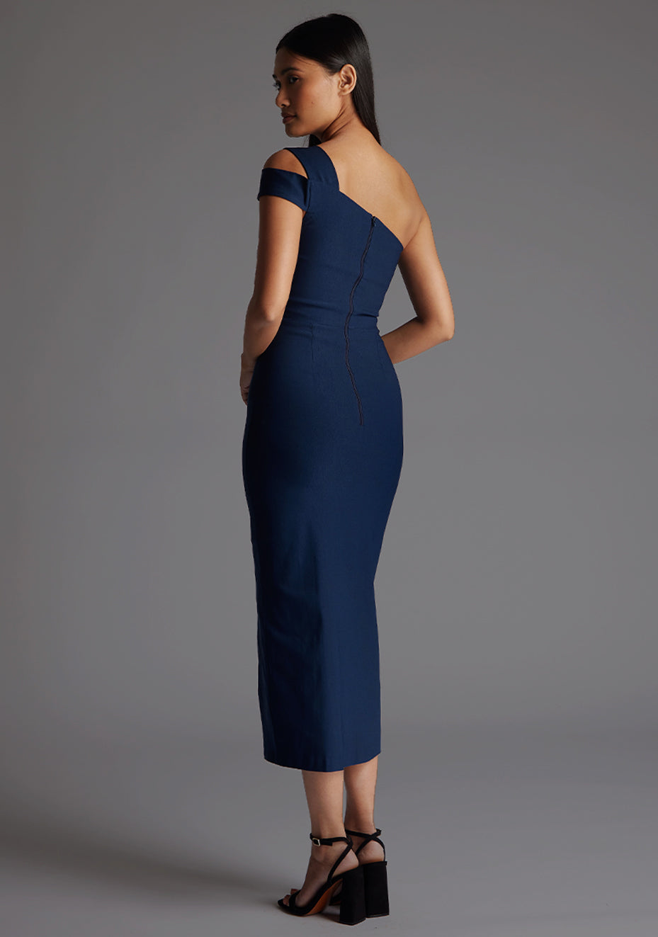Side back image of a model wearing the Vesper Porscha One Shoulder Midaxi Dress in Navy, highlighting the fitted shape and elegant one-shoulder cut.
