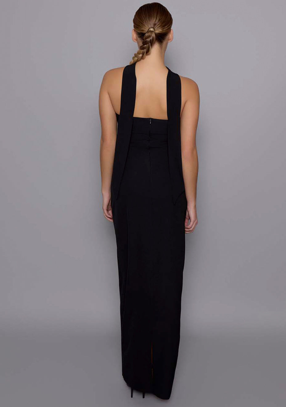 Back view of the VSPR Tiffany black dress with draped scarf halter falling down the back, clean structured finish, and column skirt silhouette.