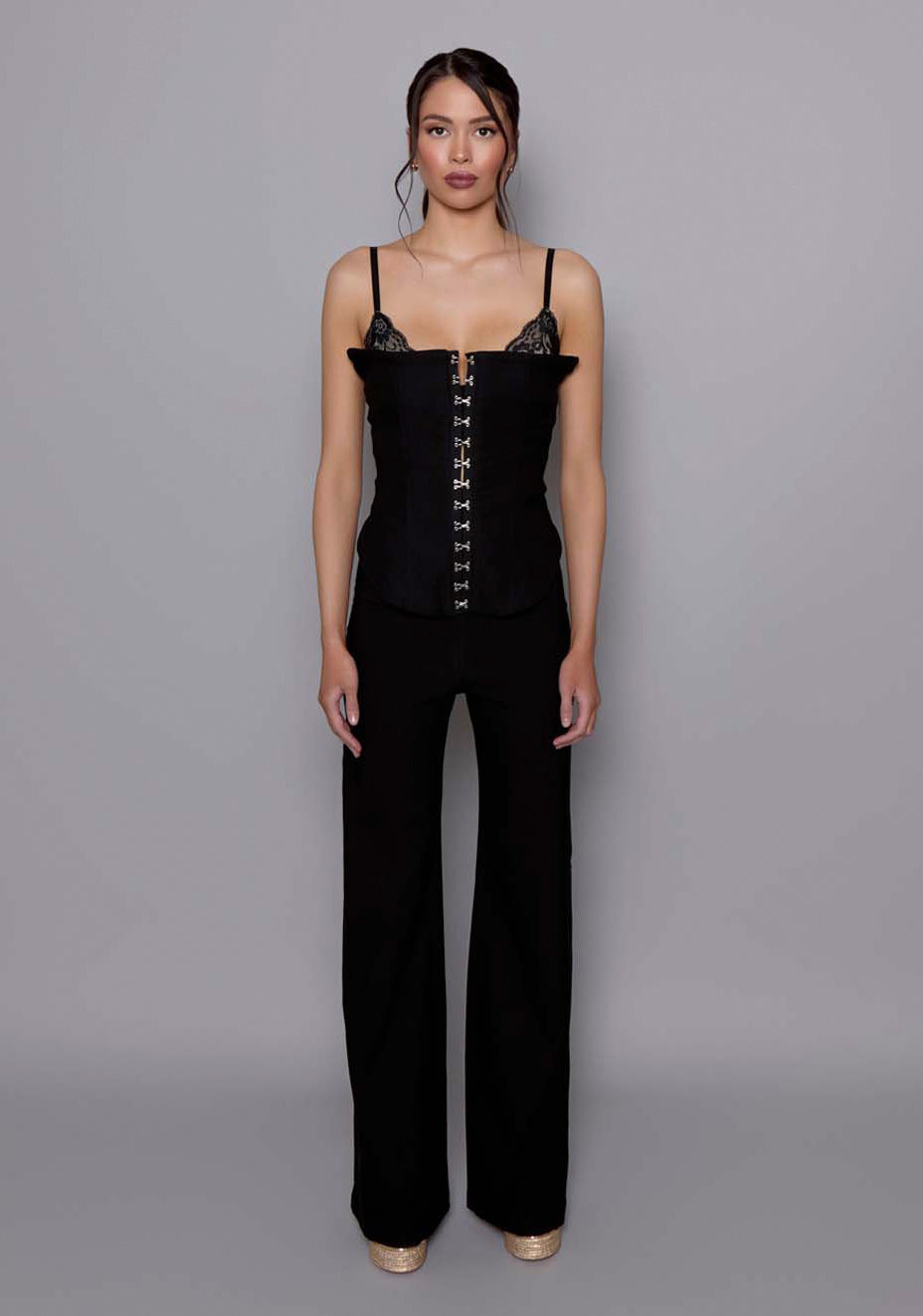 Model wearing the VSPR Tyra wide-leg tailored trousers in black, featuring a mid-to-high rise and fluid floor-skimming leg, standing against a grey studio backdrop.