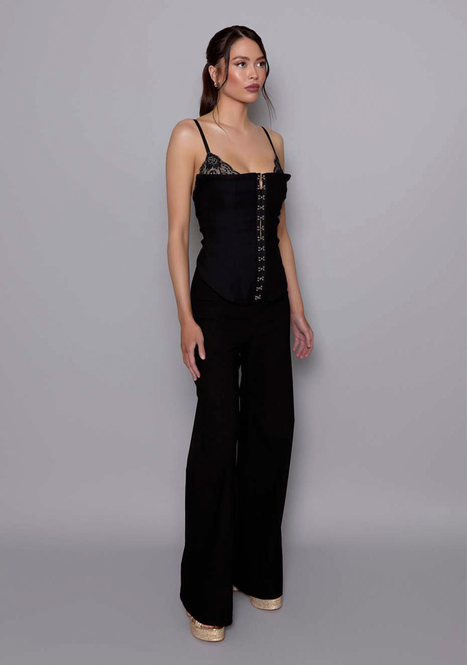 Side-front view of the VSPR Tyra black wide-leg trousers highlighting the fluid drape, mid-to-high rise waist, and clean, elongated silhouette.