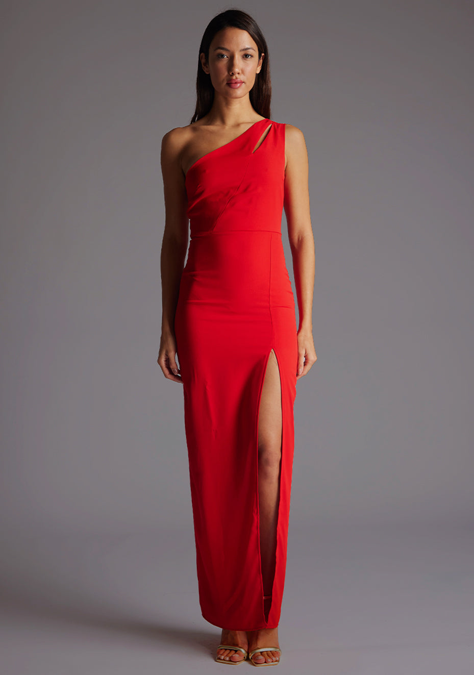 Front image of model wearing red asymmetric maxi dress with a asymmetric neckline with one shoulder detail, front bodice cut-out and front skirt split. The design featured is Vesper Verity Red Asymmetric Maxi Dress