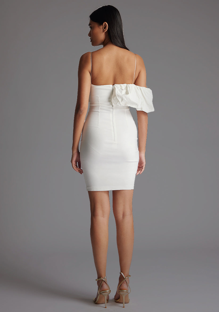 Back image of model wearing a ivory mini dress with a delicate thin straps that enhance your shoulders and a flattering puff design. The design featured is the Vesper Hattie Ivory Mini Dress.