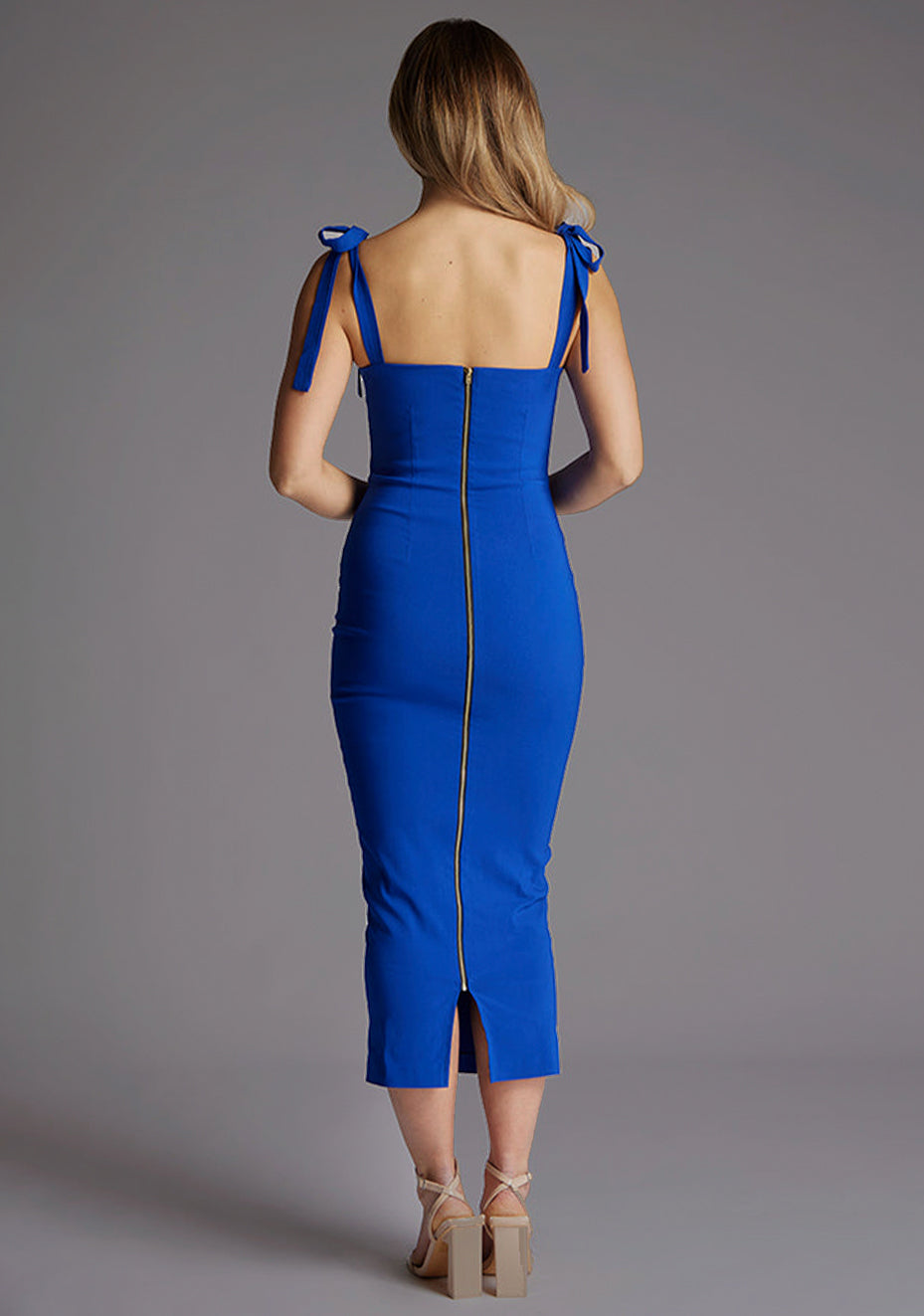 Back image of a model wearing a cobalt bow midaxi dress with a adjustable strap tie detail for a personalized fit, a square neckline with a subtle v-wire design and flattering slim fit that accentuates your natural grace. The design featured is the Vesper Letty Cobalt Bow Midaxi Dress