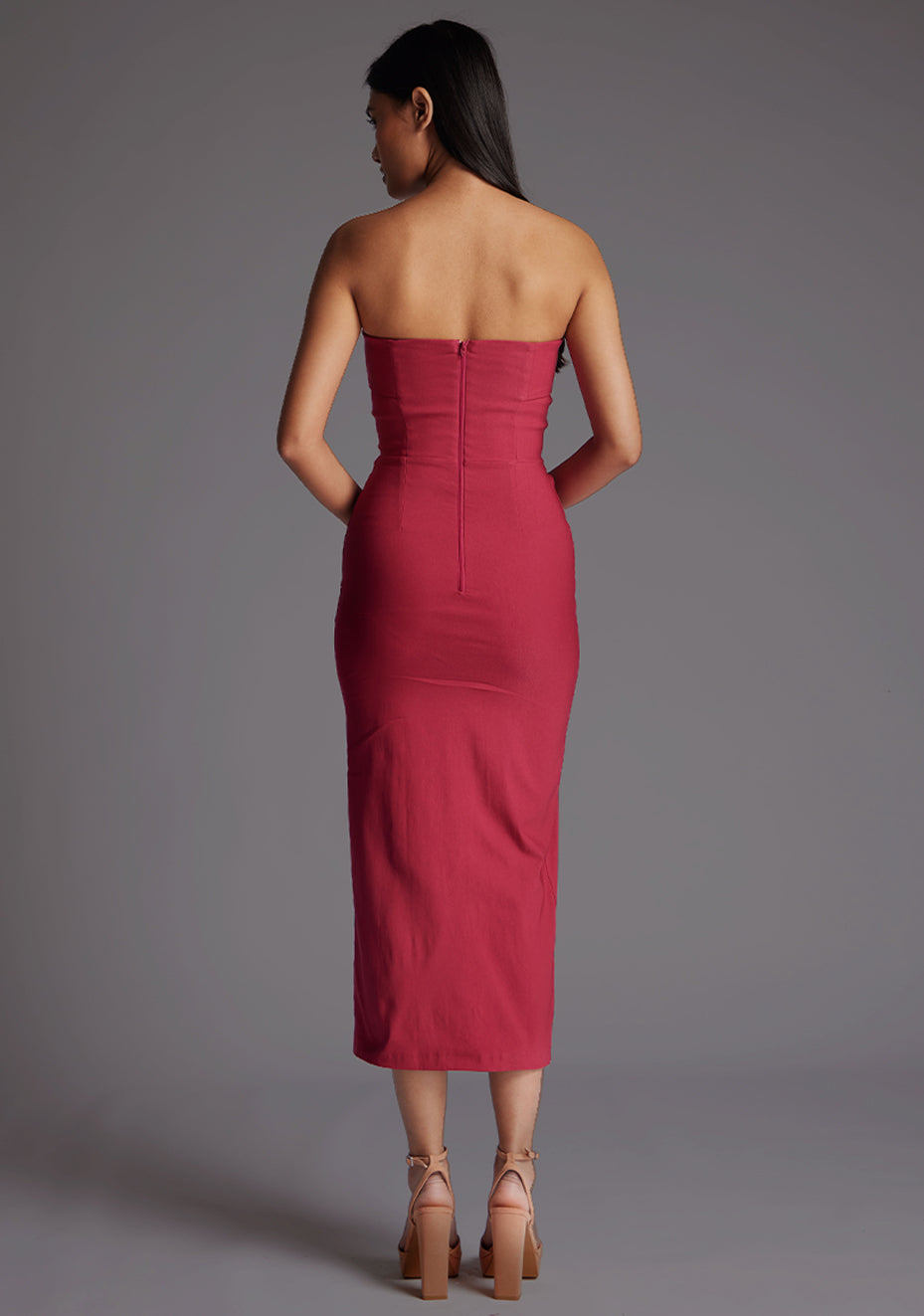 Back image of a model wearing a raspberry midaxi dress with a straight-across strapless design, side slit and bodycon fit. The design featured is the Vesper Monica Strapless Midaxi Dress in Raspberry.