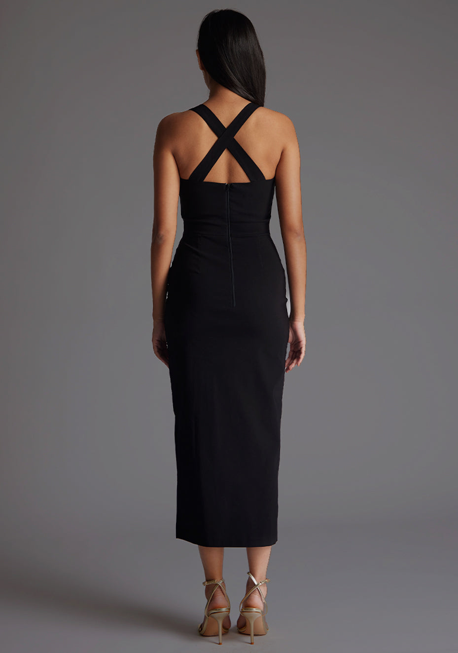 Back image of model wearing a black sweetheart midaxi dress
with a plunge sweetheart neckline with wide straps that cross at the back and a front skirt split. The design featured is the Vesper Poppy Black Sweetheart Midaxi Dress