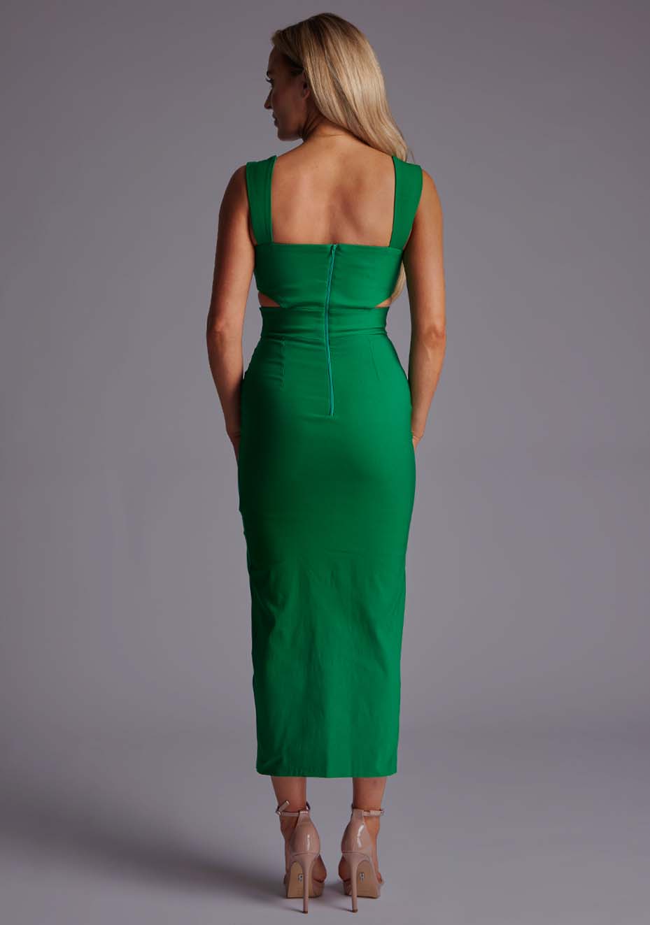 Back image of a model wearing a green cut out midaxi dress with a sweetheart neckline with wide straps, a side cut-out and front skirt split. The design featured is the Vesper Porticini Emerald Green Cut Out Midaxi Dress