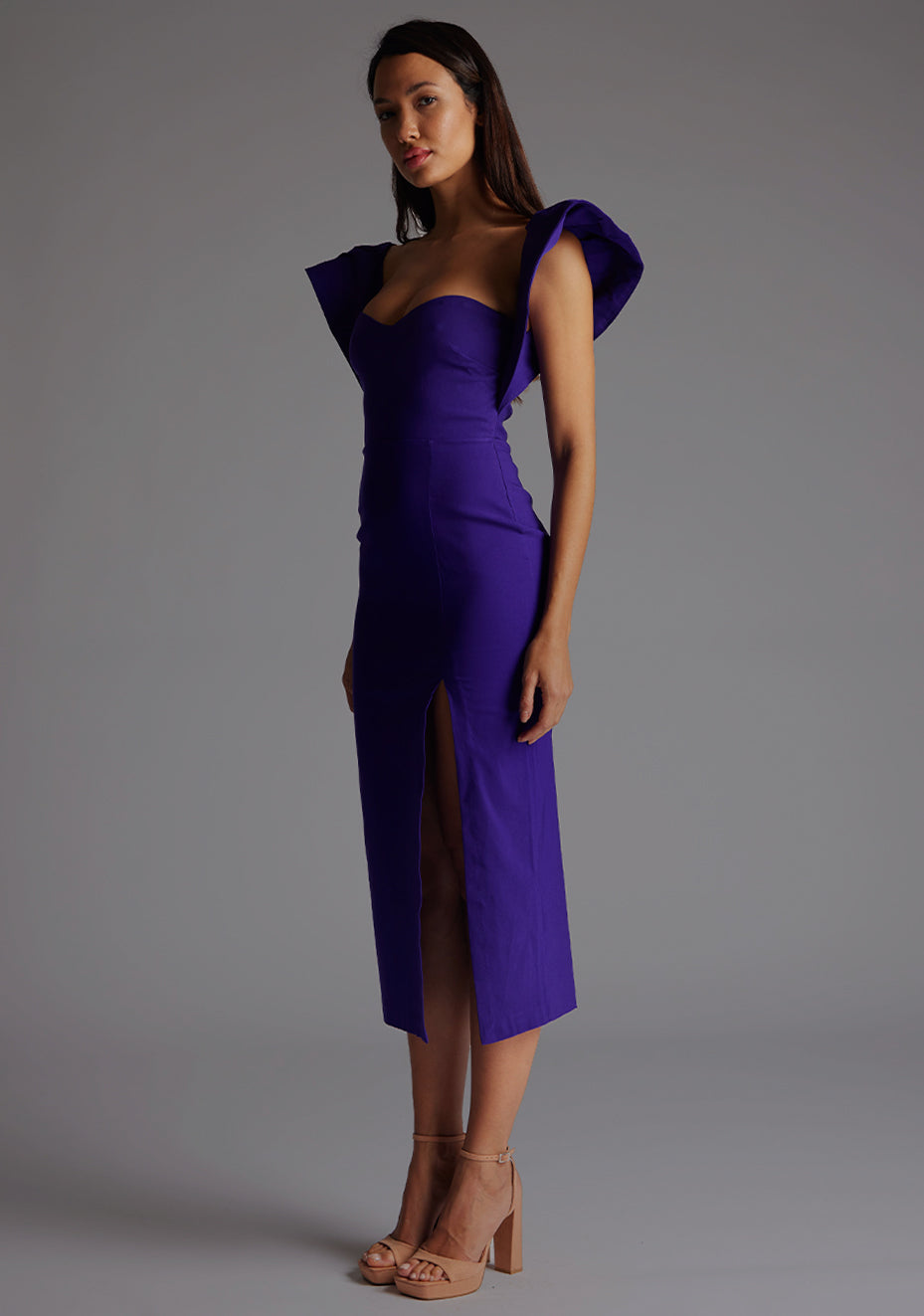 Front quarter image of model wearing a purple frill sleeve midaxi Dress with a sweetheart neckline, short frill hem cap sleeves and a front skirt split. The design featured is the Vesper Sunday Purple Frill Sleeve Midaxi Dress.