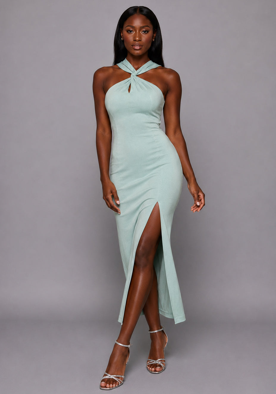 Front image of a model wearing the VSPR Aida Cross Neck Open Back Sage Midaxi Dress, showcasing the contoured silhouette, crossover neckline and flowing midaxi length against a grey studio backdrop.