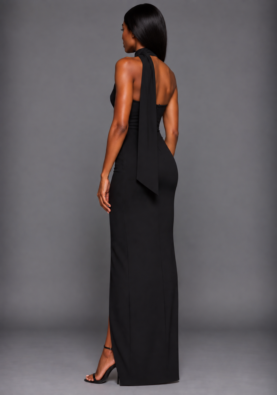 Side back image of a model wearing the VSPR Cordula Scarf Detail One Shoulder Black Maxi Dress, highlighting the elegant drape around the neckline and streamlined silhouette against a grey background.