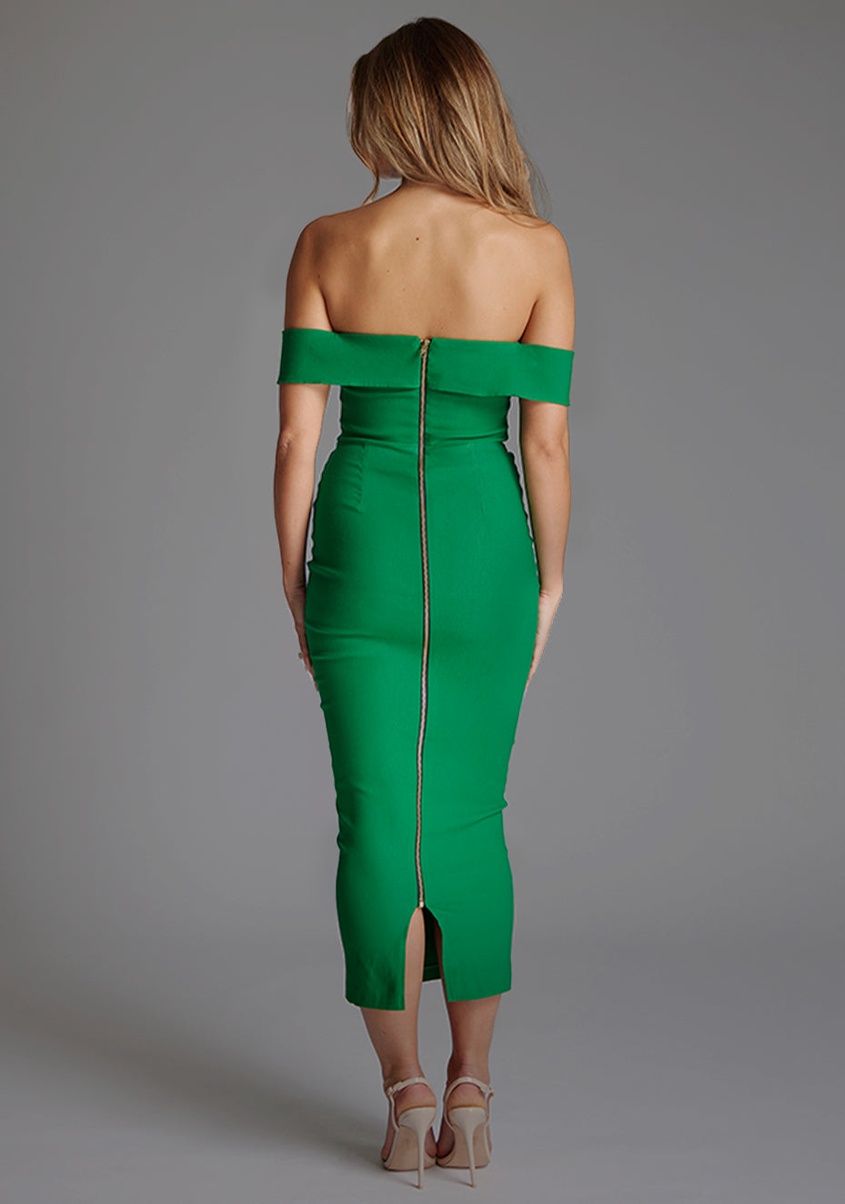 Back image of a model wearing the VSPR Daphne Bardot Cut Out Emerald Green Midaxi Dress, showcasing its sleek slim-fit shape and elegant midaxi length against a grey studio backdrop.