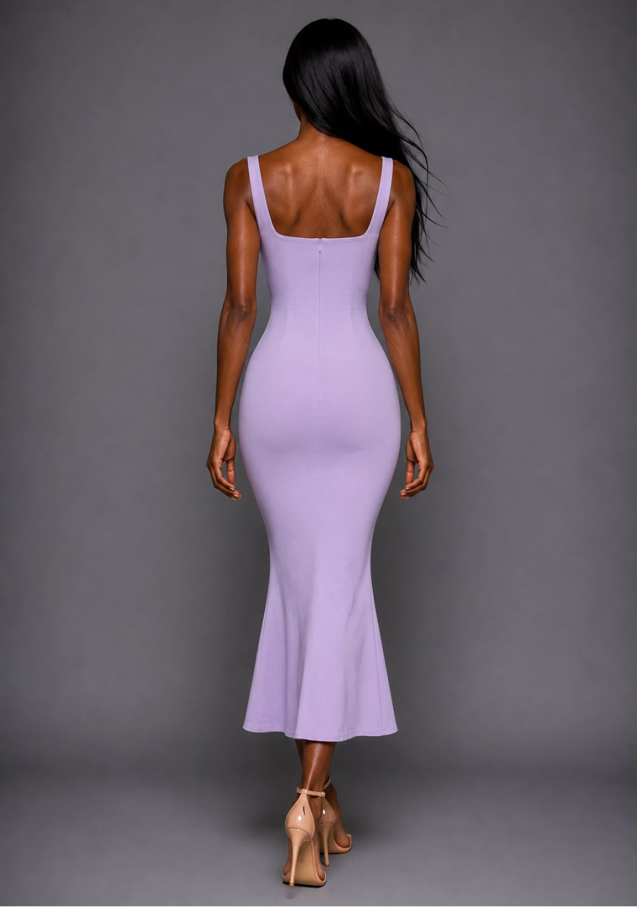 Back view of a model wearing the VSPR Marianna Lilac Midaxi Dress showcasing the clean back design, figure-enhancing fit and graceful fishtail silhouette against a grey backdrop.