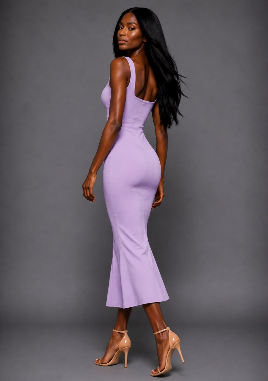 Side back image of a model wearing the VSPR Marianna Lilac Midaxi Dress highlighting the flattering body-skimming design, wide straps and fishtail hem against a grey backdrop