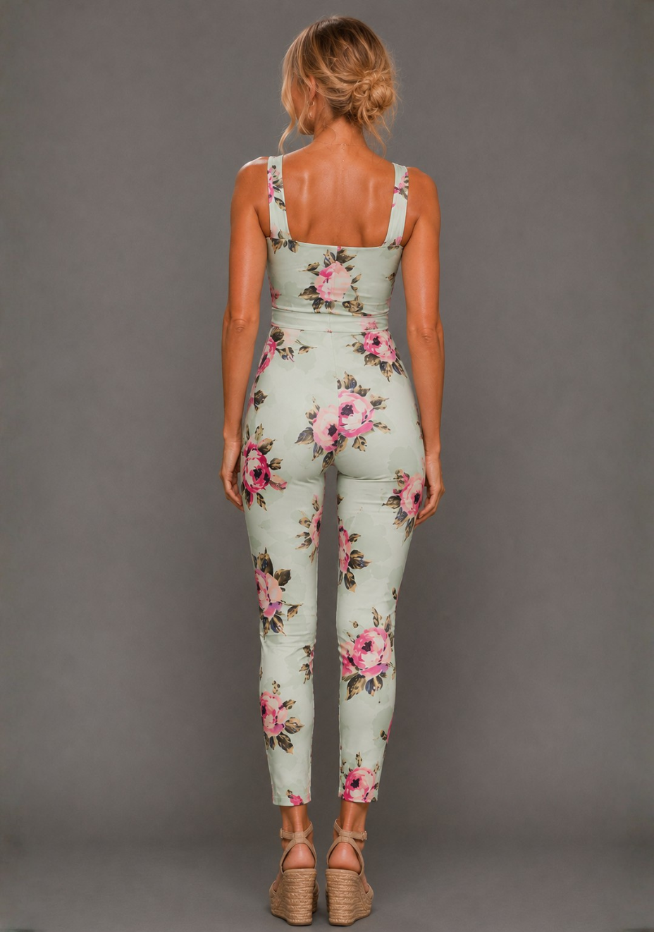 Back image of a model wearing the VSPR Nala Square Neckline Mint Floral Jumpsuit in Mint Floral with a self-tie waist belt and sleek tapered legs, standing against a grey studio backdrop