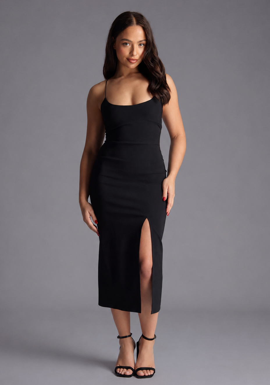 Woman wearing the Vesper Petite beryl black midaxi dress with a thigh slit on a grey background